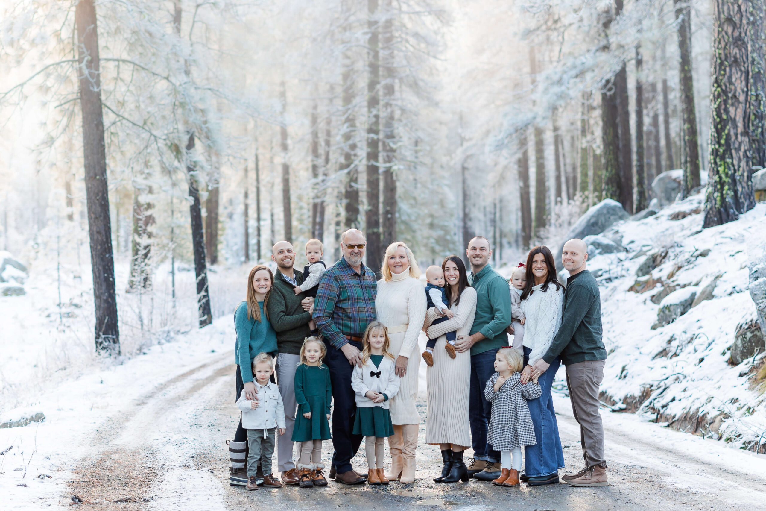 A large extended family stands in a snow covered dirt road at sunset