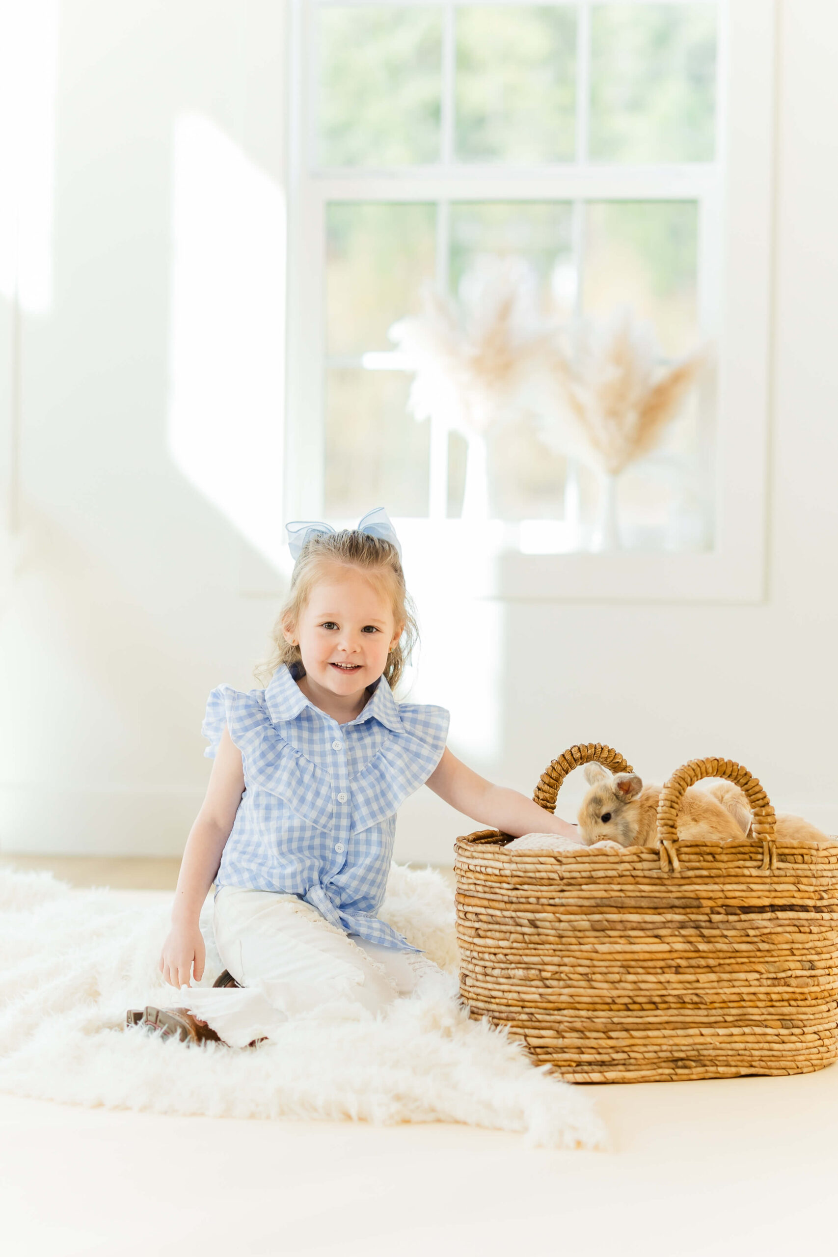 A young girl in a blue blouse sits on the floor of a studio playing with a bunny in a basket before heading to playgrounds in leavenworth, wa
